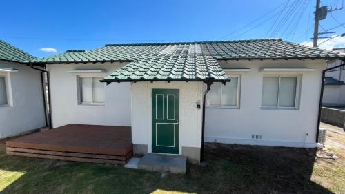 a white house with a green door and a deck at Fukuoka - House / Vacation STAY 4644 in Fukuoka