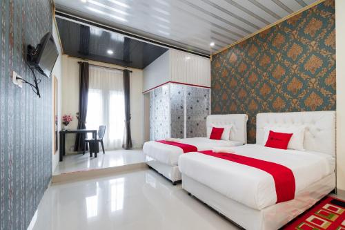two beds in a hotel room with red pillows at RedDoorz Syariah near Minangkabau International Aiport in Duku
