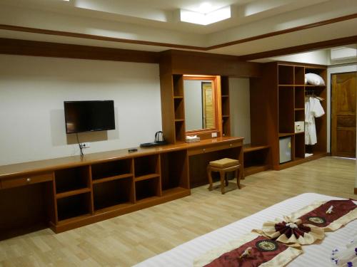 a hotel room with a bed and a tv and shelves at The Sunset Beach Resort - Koh Kho Khao in Ko Kho Khao