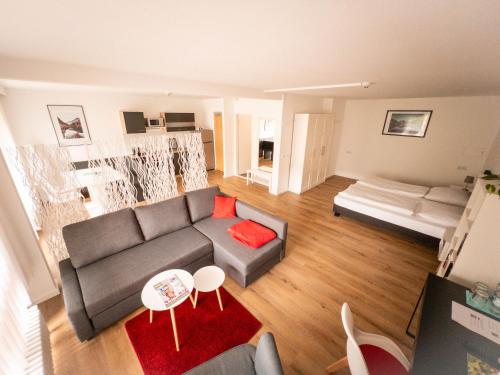- un salon avec un canapé gris et un tapis rouge dans l'établissement Hotel Quellenhof Bad Urach, à Bad Urach