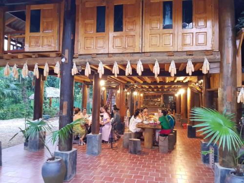 a group of people sitting at tables in a restaurant at Vu Linh Palm House Homestay - Bungalow in Yen Bai
