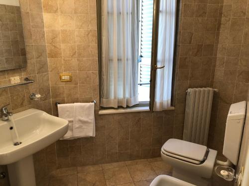 ein Bad mit einem Waschbecken, einem WC und einem Fenster in der Unterkunft Centro Paolo VI in Brescia