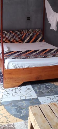 a bed with a wooden frame and a tile floor at Akwa Guesthouse Cotonou in Cotonou