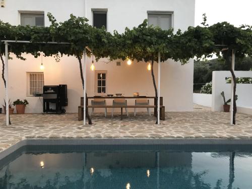 un patio con una mesa y un piano junto a la piscina en Casa Olivo en Iznájar