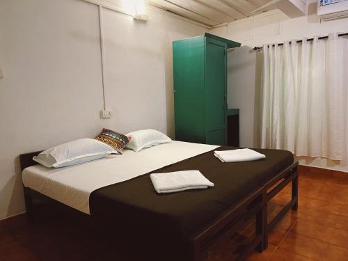 a bedroom with a bed with a green cabinet at Bunk house Fort Kochi in Cochin