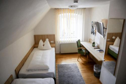 een kleine kamer met 2 bedden en een bureau bij Weinstube Sinas Brettl in Nördlingen
