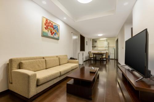 a living room with a couch and a flat screen tv at Belgravia Serviced Residence Wuxi in Wuxi