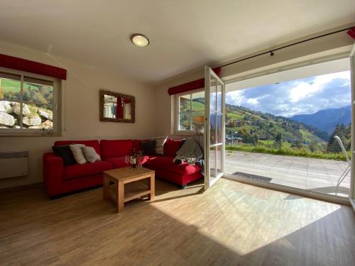 a living room with a red couch and a sliding glass door at Genieten in Saalbach, Alpenresort Saalbach Top D1 by Droomvilla in Saalbach Hinterglemm