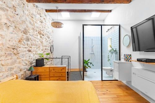 1 dormitorio con pared de piedra y cama amarilla en Singulary House-Loft with AC Downtown - Dodo et Tartine, en Hyères