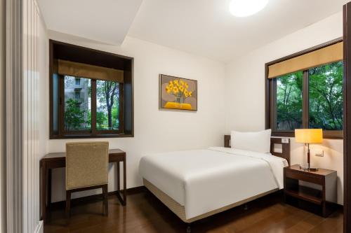1 dormitorio con cama, escritorio y silla en Belgravia Serviced Residence Wuxi, en Wuxi