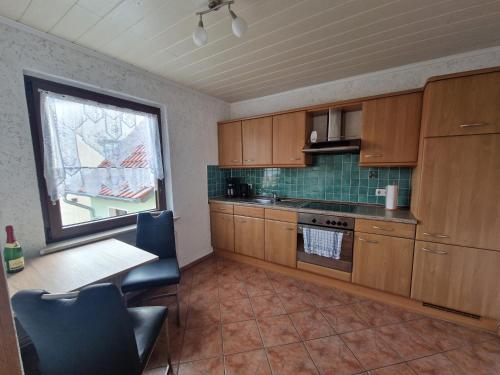 a kitchen with wooden cabinets and a table and a window at Ferienwohnung am grünen Haus in Garz-Rügen