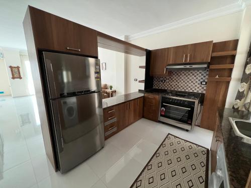 a kitchen with a stainless steel refrigerator and cabinets at Modern apartment in Madinat Al Ashir min Ramadan