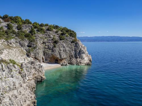 a cliff with a beach next to the water at Apartment Rea with Pool in Brseč