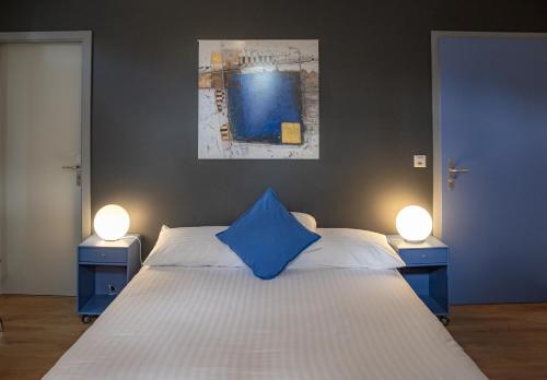 Un dormitorio con una almohada azul en una cama con dos luces en Au Boeuf Rouge, en Crassier