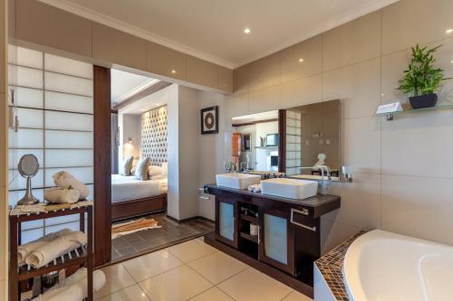 a bathroom with two sinks and a tub and a bedroom at Inverdoorn Game Reserve Lodge in Breede River DC