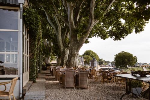 a table and chairs under a tree next to a building at Hotel Restaurant Belvédère in Schoonhoven
