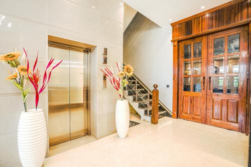 two white vases with flowers in them in a hallway at Hotel Grand Cabbana By Levelup Hotels in Amritsar
