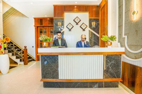 two men sitting at a counter in a lobby at Hotel Grand Cabbana By Levelup Hotels in Amritsar