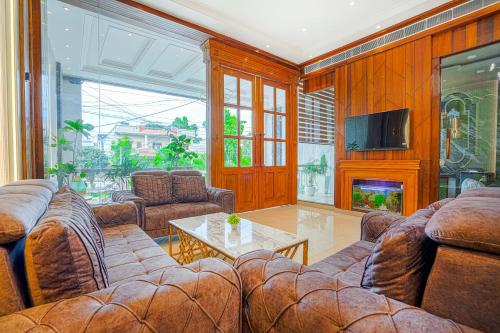 a living room with leather couches and a fireplace at Hotel Grand Cabbana By Levelup Hotels in Amritsar