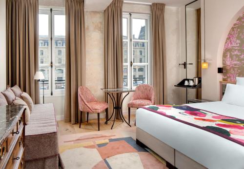 ein Hotelzimmer mit einem Bett und einem Tisch mit Stühlen in der Unterkunft Les Rives de Notre-Dame in Paris