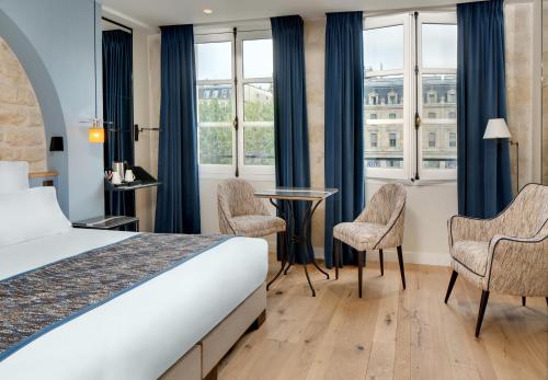 a hotel room with a bed and a table and chairs at Les Rives de Notre-Dame in Paris