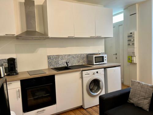 a kitchen with a washing machine and a microwave at LE VICTOR HUGO - Wifi - Centre ville - PROPERTY RENTAL NM in Périgueux