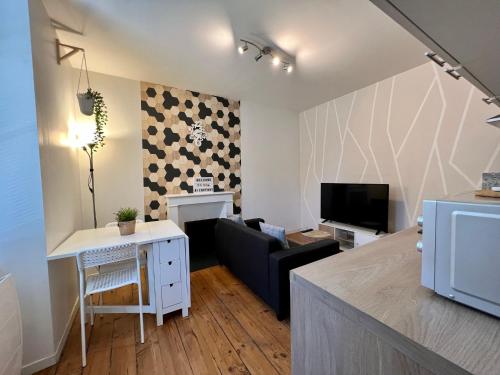 a living room with a couch and a table and a television at LE VICTOR HUGO - Wifi - Centre ville - PROPERTY RENTAL NM in Périgueux