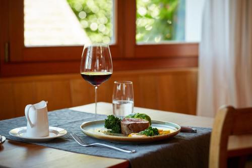 a table with a plate of food and a glass of wine at Boutique-Hotel Schlüssel in Beckenried