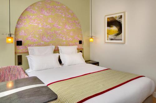a bedroom with a large white bed and a pink wall at Les Rives de Notre-Dame in Paris