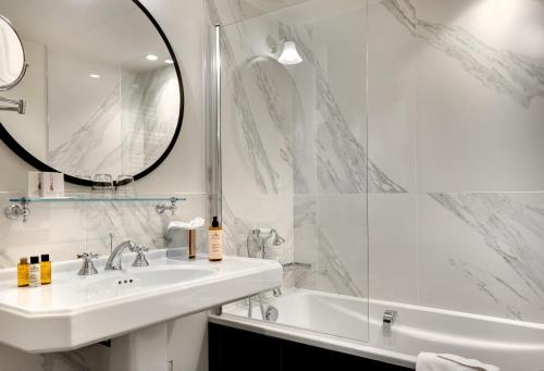 La salle de bains est pourvue d'un lavabo, d'une baignoire et d'un miroir. dans l'établissement Les Rives de Notre-Dame, à Paris