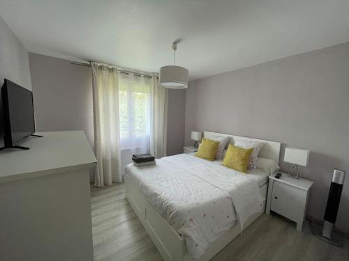 biała sypialnia z łóżkiem z żółtymi poduszkami w obiekcie Maison tout confort en Touraine 4 chambres w mieście Fondettes