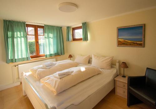 1 cama blanca grande en un dormitorio con ventanas en Inselhotel Kapitän Tadsen / Amrum, en Nebel