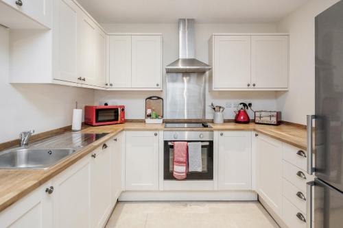 a kitchen with white cabinets and a sink at MPL Apartments - Queens Broadway F4 in Watford