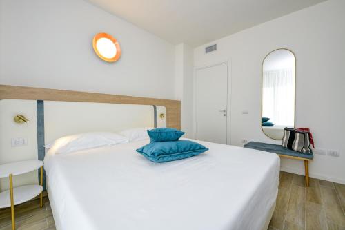 a bedroom with a white bed with blue pillows on it at Residence Sunlight in Lido di Jesolo