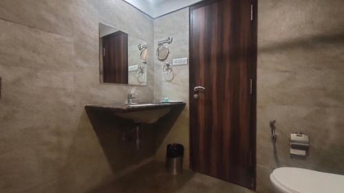 een badkamer met een wastafel en een spiegel bij Hotel Sach Regency in Anand