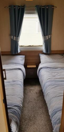two beds in a room with a window at Living Easy Staycations at Tattershall Lakes in Tattershall