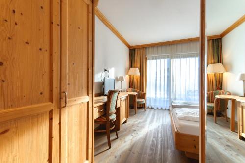 a hotel room with a desk and a bedroom at Residence Hotel Alpinum in Campo Tures