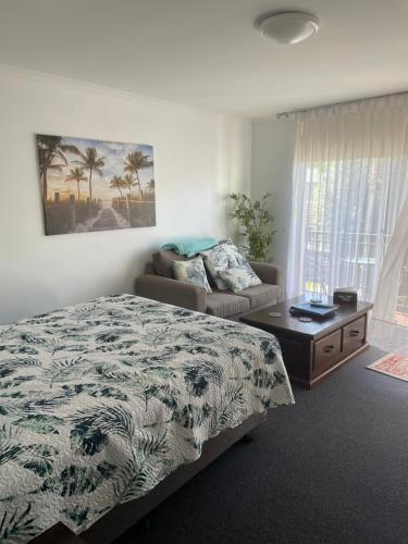 a bedroom with a bed and a couch and a table at Tranquility at Mandurah Apartments in Mandurah