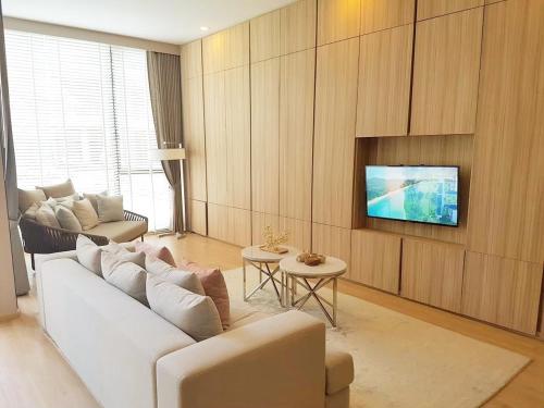 uma sala de estar com um sofá branco e uma televisão em Baan Maikhao pool villa em Mai Khao Beach