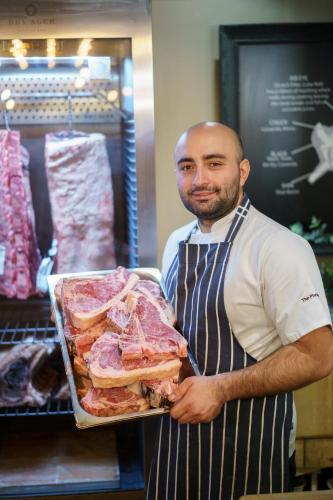a man holding a tray of meat in a store at Chapter House in Salisbury