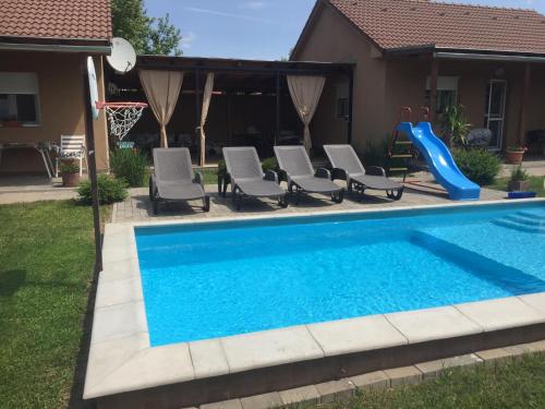 a pool with chairs and a slide in a yard at Kökszi Beach Nyaralóházak in Balatonszabadi