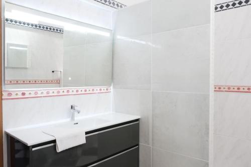 uma casa de banho branca com um lavatório e um espelho em Villa Beauregard em Sainte-Luce