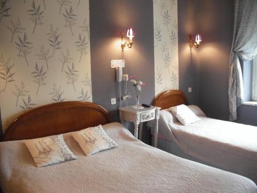 two beds in a hotel room with flowers on the wall at Hotel Le Clos du Montvinage in Étréaupont