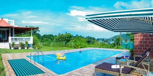 a backyard swimming pool with an umbrella and a toy raft at Spicy Mango Ocean Paradise - Luxurious Sea View Villa In Alibaug in Christpāda