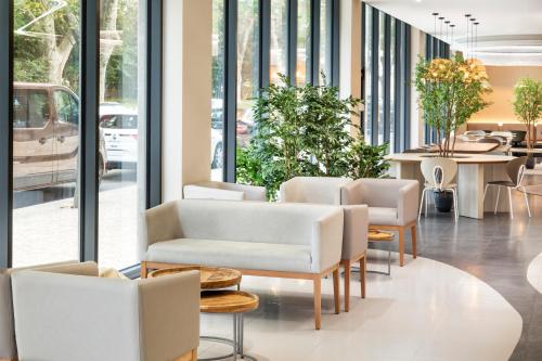 a lobby with white chairs and tables and windows at B&B HOTEL Lisboa Montijo in Montijo
