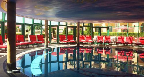 a pool with red chairs in a building at Victor's Residenz-Hotel Schloss Berg in Nennig