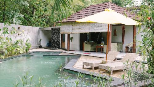 ein Haus mit Swimmingpool und Sonnenschirm in der Unterkunft Lullabi Lumbung Villa in Lajor