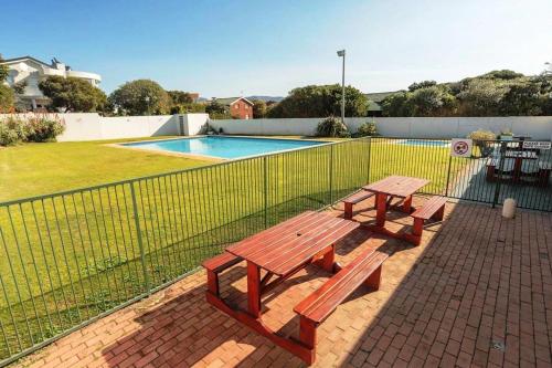 a picnic table next to a fence next to a pool at Aurora's Rest 47 in Fisherhaven