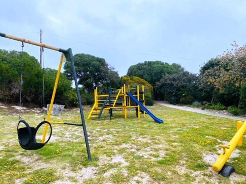 an empty playground with a swing set in a field at Aurora's Rest 47 in Fisherhaven