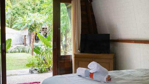 Zimmer mit einem Bett, einem TV und einem Handtuch. in der Unterkunft Lullabi Lumbung Villa in Lajor